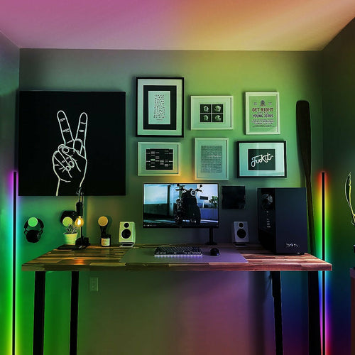 Modern home office with a desk, computer setup, and colorful LED lights on the wall.
