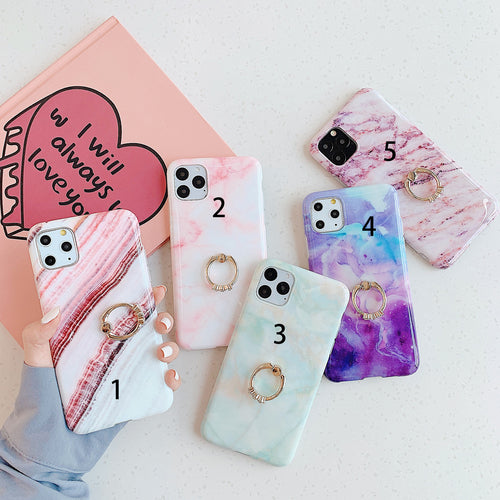 Five phone cases with marble patterns and ring holders on a white background