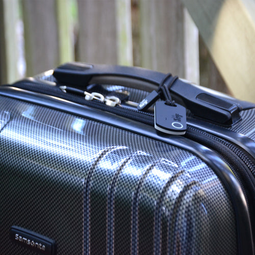 Black Samsonite suitcase with a tag on a blurred background