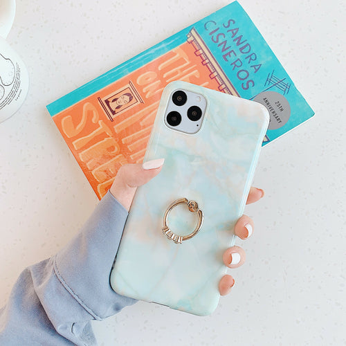 Phone case with ring holder held by a hand, book in the background