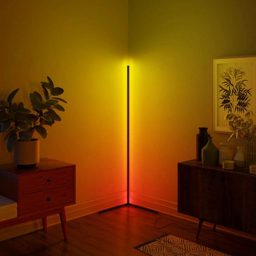 Modern floor lamp casting a warm glow in a room with furniture and decor.