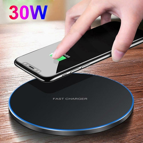 Hand placing a smartphone on a wireless charger with '30W' text above, on a wooden surface.